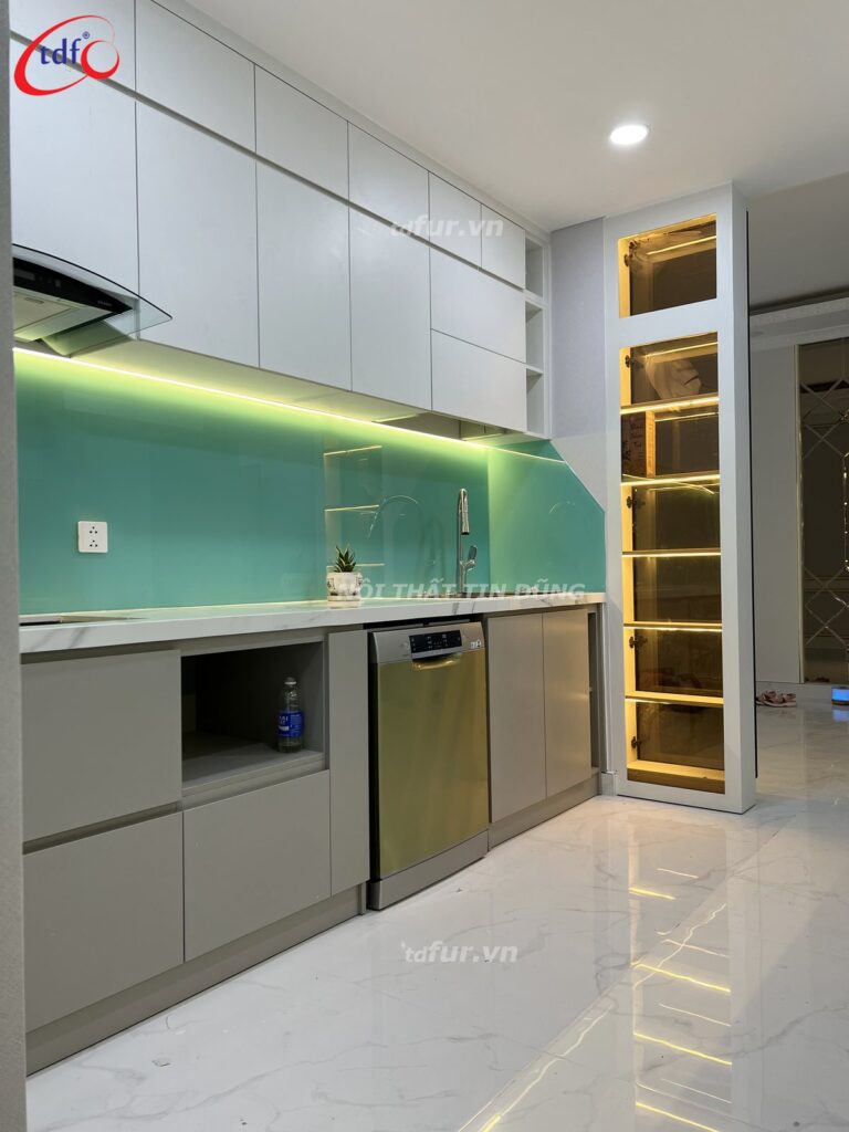 Skyline Villa – Kính bếp xanh ngọc và tủ đèn viền vàng